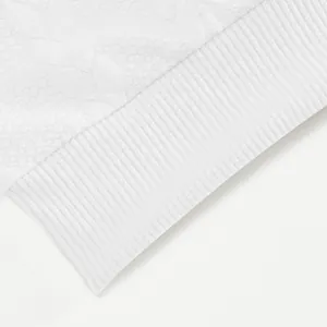 Gedetailleerde close-up van de witte jacquard stof en de geribbelde manchetten