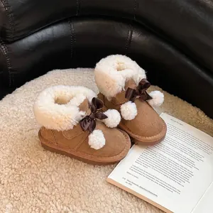 Dettaglio di stivali da neve marroni per bambina con fodera in pelliccia e fiocco decorativo