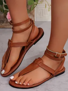 Detailed view of brown gladiator thong sandals with multiple ankle straps and buckle