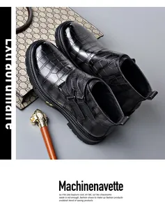 Detalle de los botines Chelsea en piel negra brillante con relieve de cocodrilo y hebillas.