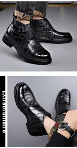 Detalle de botines Chelsea de cuero negro con textura de cocodrilo y elegante hebilla