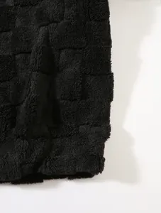 Nahaufnahme von schwarzem Sherpa-Fleece-Stoff mit einem geprägten Schachbrettmuster