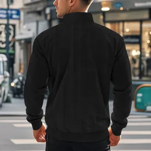 Achteraanzicht van een zwart herensweatshirt met kabelpatroon en opstaande kraag op straat.