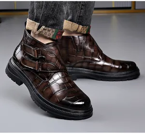 Primer plano de botines de hombre en cuero marrón con estampado de cocodrilo y hebillas.