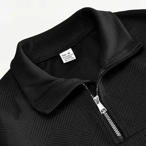 Detailopname van herensweatshirt met kwartrits, zwarte jacquardtextuur en waslabel.