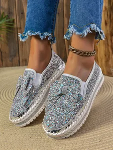 Close-up detail of women's sparkling sequin flat shoes featuring a decorative bow