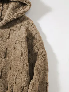 Makro-Detail des braunen Kapuzen-Lammwoll-Sweatshirts mit markanter Schachbrett-Textur