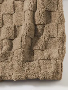 Makroansicht der weichen Textur des braunen Lammhaar-Fleece-Stoffs mit Schachbrettmuster