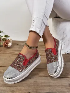Primer plano de mocasines brillantes de mujer con purpurina y punteras de pedrería.