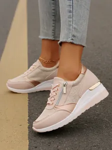 Close-up of stylish pink wedge sneakers with side zipper and metallic accents on road.