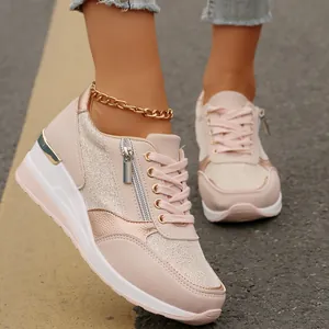 Close-up side view of stylish pink wedge sneakers with rose gold accents and zippers.