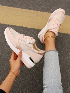 Close-up of pink platform wedge sneakers with metallic accents and lace-up design