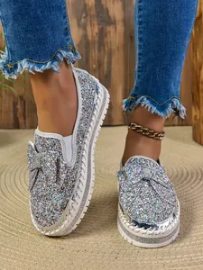 Close-up of glittery sequins and bow detail on fashionable silver flat shoes