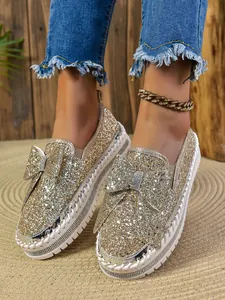 Detailed macro view of sparkly gold glitter flat shoes with a stylish oversized bow
