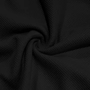 Détail macro du tissu en tricot gaufré noir montrant la texture premium