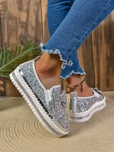 Close-up detail of sparkling multicolor glitter loafers featuring bow and thick white soles