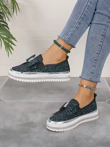 Detailed close-up view of dark green glitter flat shoes with a stylish decorative bow tie