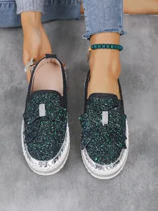 Close-up of glitter slip-on loafers with rhinestone bow detail and white platform sole