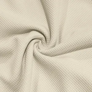 Gros plan sur la texture du tissu en maille gaufrée blanc cassé pour vêtements homme.