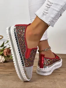 Detalle de los mocasines de plataforma con purpurina para mujer y ribetes rojos.