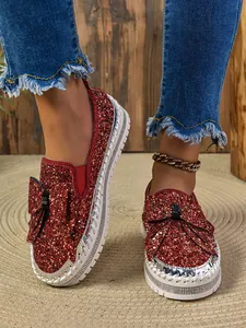 Glamorous sparkling red sequined flat shoes with bow detail worn by model
