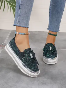 Detailed macro view of shimmering sequined women's flat shoes with a large bow