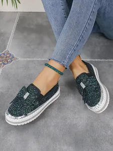 Detailed view of women's dark green glittery flat shoes with bow and silver trim