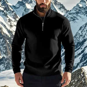 Outdoor-Detail eines schwarzen Herren-Sweatshirts mit Viertelreißverschluss vor Bergkulisse.