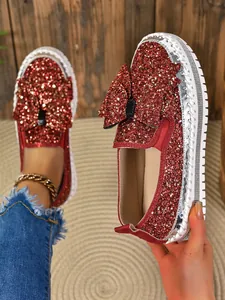 Close-up of red glitter women's loafers featuring a large bow and thick white sole