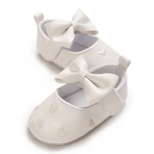 Vue détaillée de chaussures de princesse bébé blanches avec nœuds et cœurs brodés.