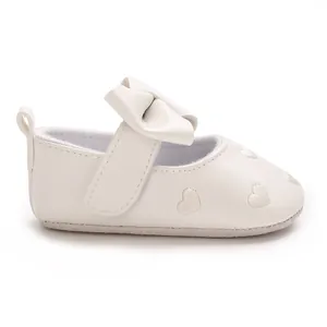 Vue détaillée de chaussure bébé avec broderie de cœur blanc et un nœud papillon décoratif