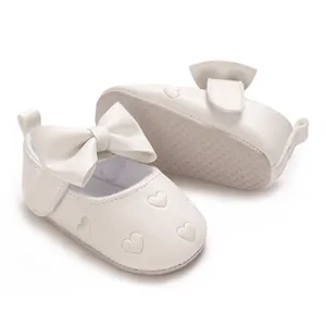 Vue détaillée de chaussures blanches pour bébé avec broderie cœur et nœud élégant
