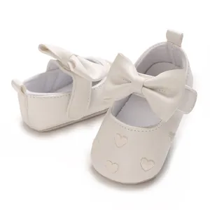 Détail de chaussures bébé crème avec cœurs brodés et un grand nœud décoratif