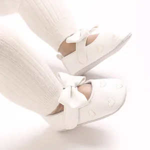 Vue détaillée de chaussures blanches pour bébé avec cœurs brodés et un grand nœud