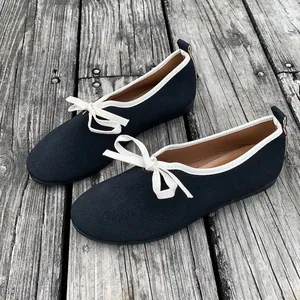 Elegante zwarte Mary Jane-ballerina's met witte strik en zachte zool op hout.