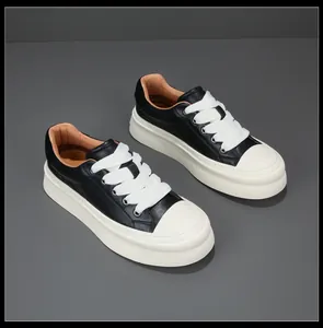 Detailed view of stylish black and white leather platform sneakers with wide laces.