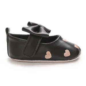 Vue détaillée latérale d'une chaussure pour bébé noire avec broderie cœur et nœud