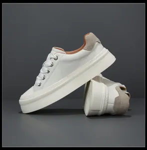 Close-up of white leather men's sneakers with thick platform soles and wide laces.