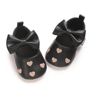 Détail de chaussures de princesse bébé noires avec cœurs brodés et un grand nœud