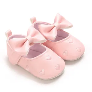 Détail de chaussures de marche roses pour bébé avec cœurs brodés et grand nœud