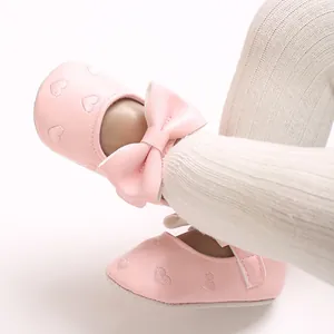 Détail des chaussures bébé roses avec broderie en cœur et nœud papillon