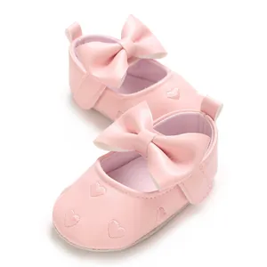 Détail de chaussures roses pour bébé avec cœurs brodés et un grand nœud papillon