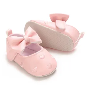 Détail de chaussures premier pas rose pour bébé avec broderie cœur et nœud