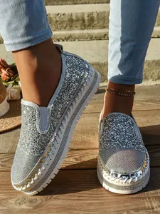 Primer plano de mocasines con plataforma plateados con purpurina y pedrería para mujer