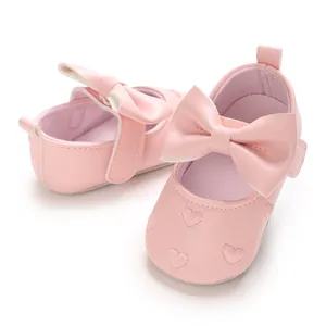 Vue détaillée de chaussures bébé roses avec broderie cœur et grand nœud papillon