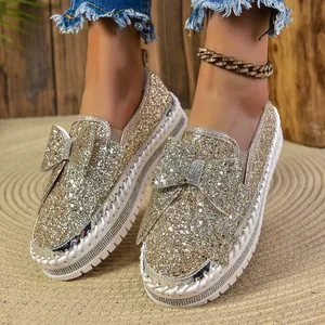 Stylish gold sequin flat shoes for women with large bow detail and white sole.
