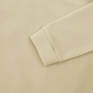 Gros plan sur le poignet côtelé et le tissu d'un sweat à capuche beige pour homme