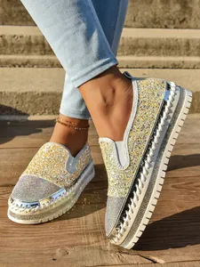 Detalle de mocasines amarillos con purpurina y pedrería con suelas de plataforma blancas gruesas