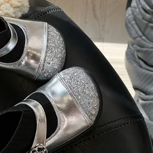 Close-up of girls silver Mary Jane sock boots with glitter toe caps and knit fabric.