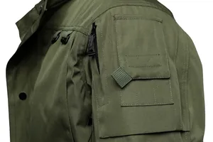 Close-up detail of olive green tactical jacket shoulder pocket and durable fabric texture